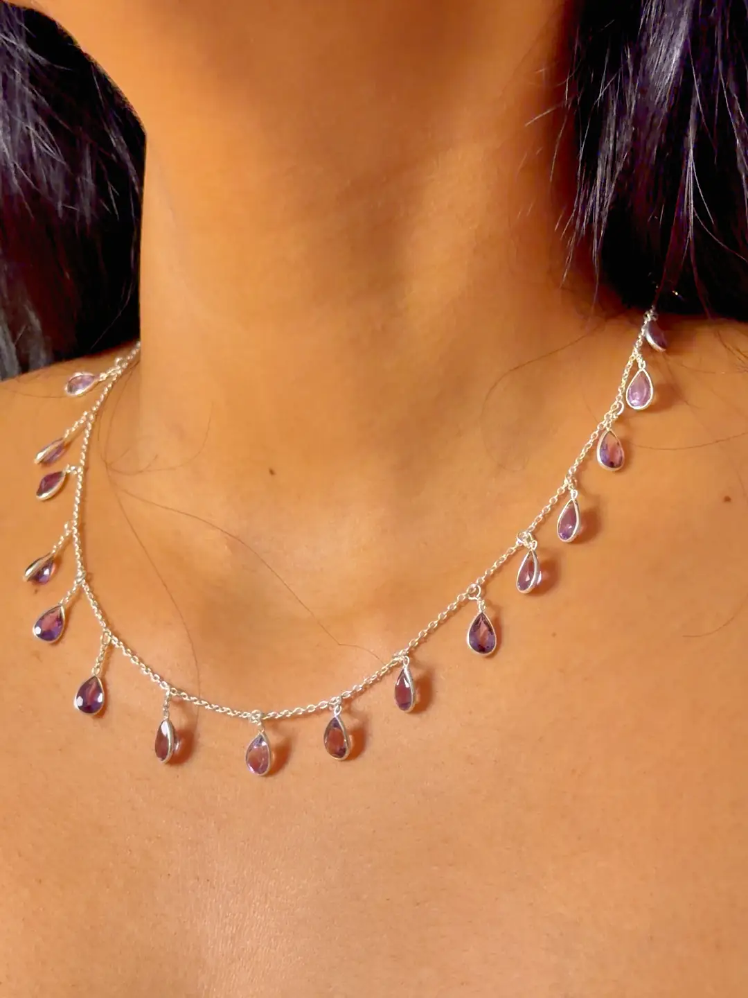 Barkha amethyst drop necklace worn at the collarbone, the faceted purple pears resting on skin