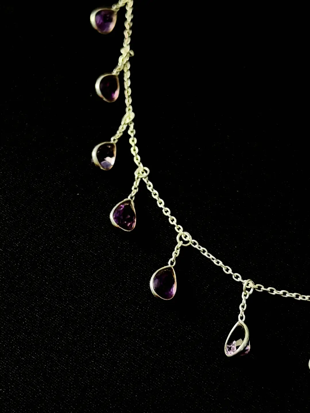 Close view of the faceted amethyst pears in their slim silver bezels