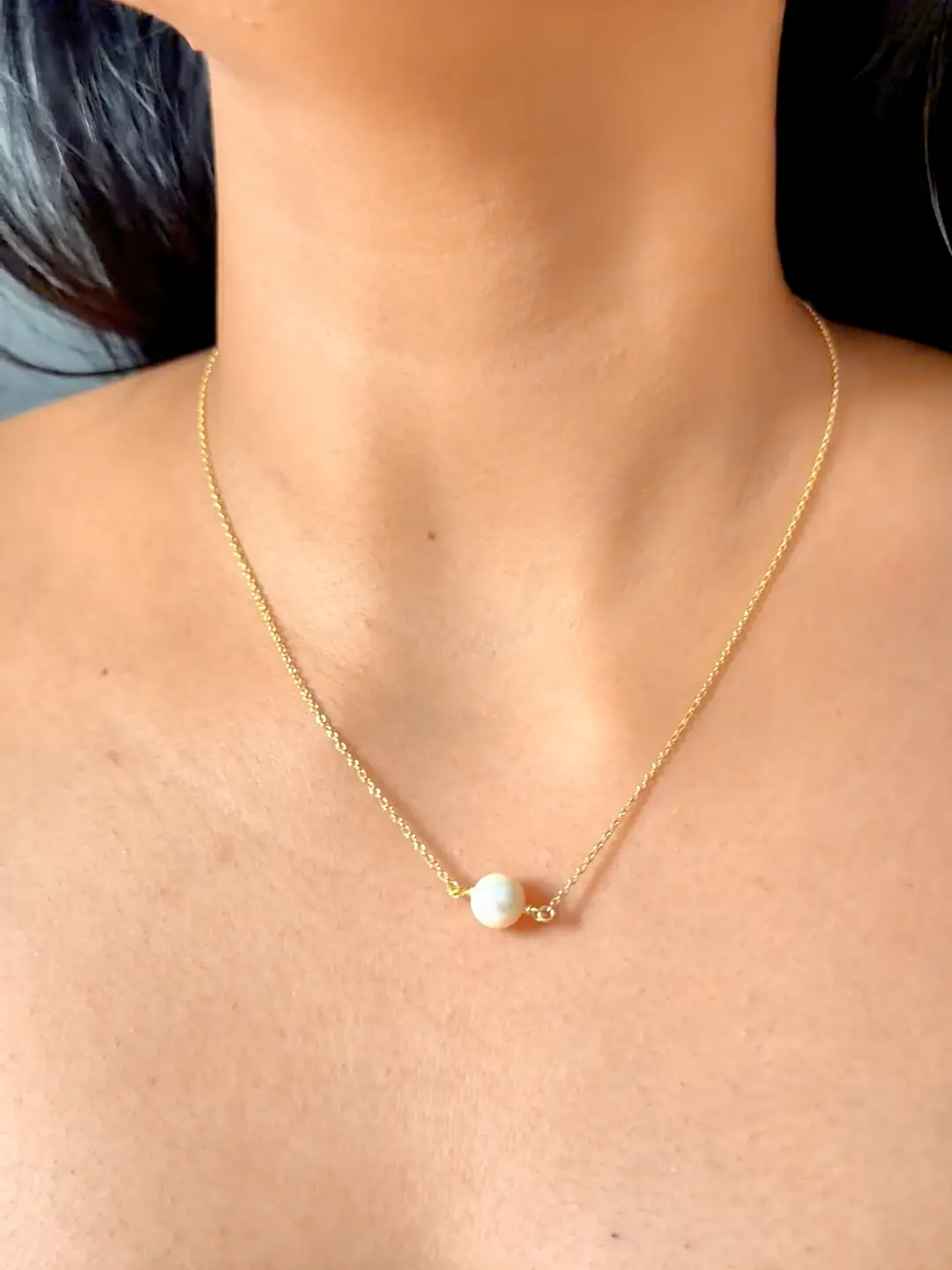 The Bindu pearl resting at the collarbone, its chain nearly invisible