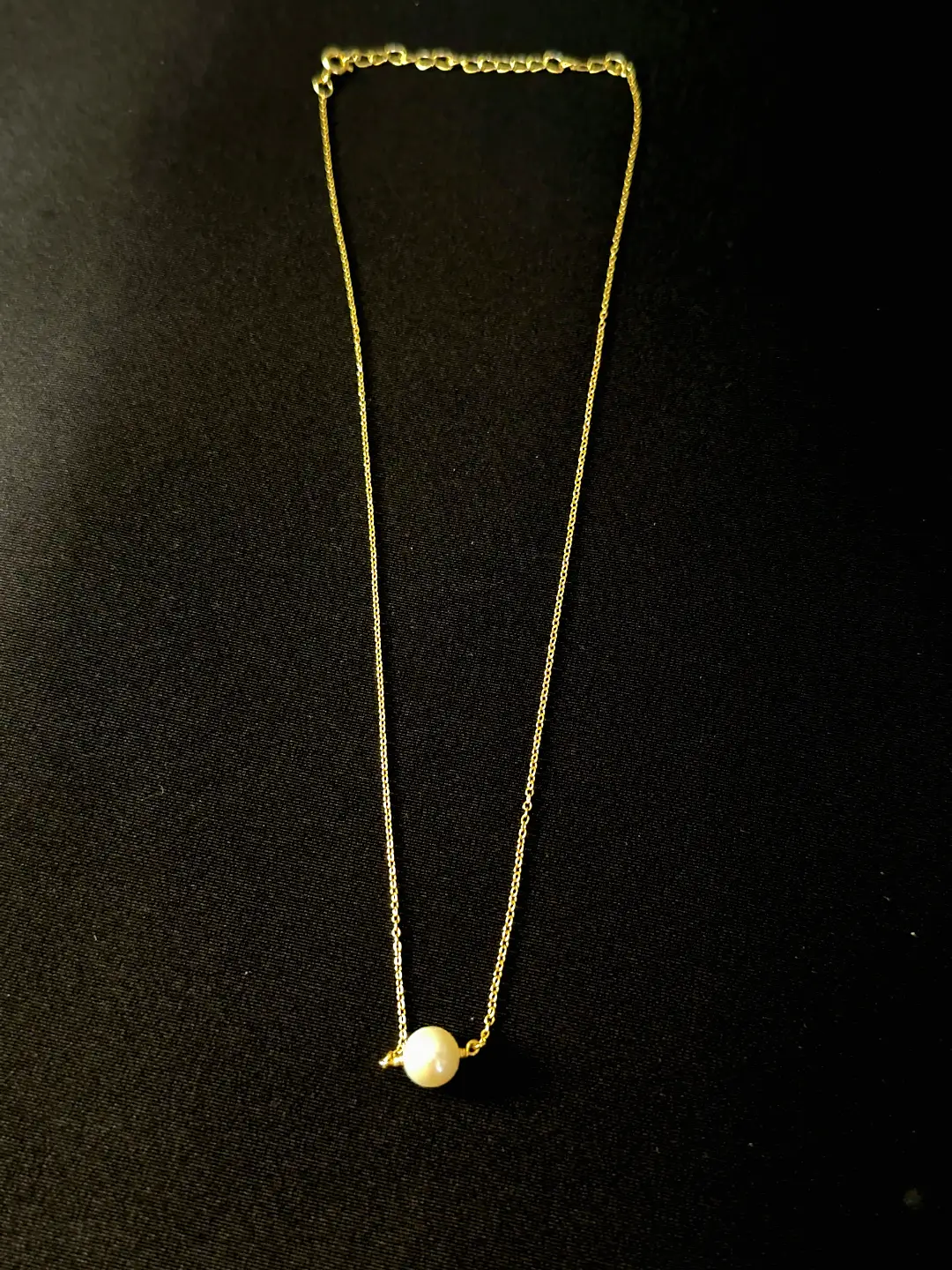 Close view of the Bindu freshwater pearl threaded on its gold chain
