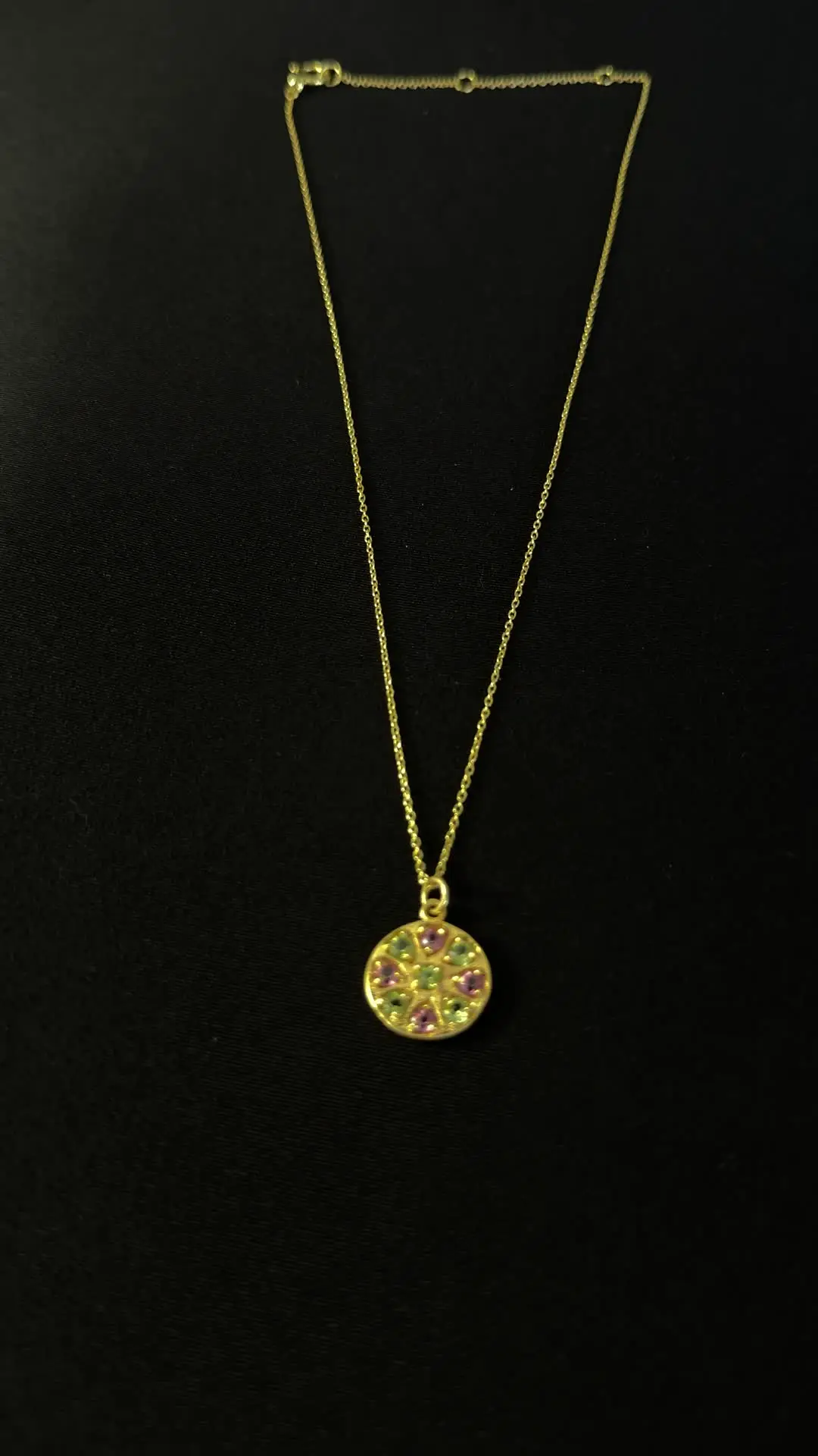 Chakra pendant — a gold disc set with peridot and pink tourmaline in a rosette