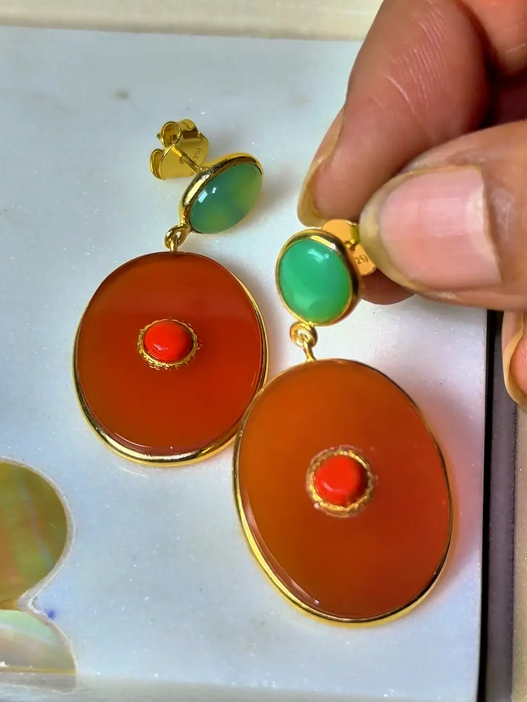 A Gulmohar earring held in the hand, showing the chrysoprase stud and push-back fitting