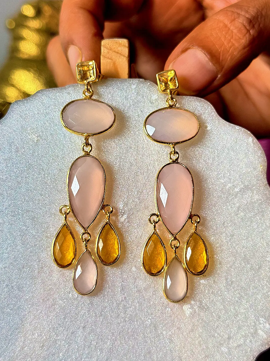 Jhumar chandelier earrings held in the hand, showing their drop length and scale