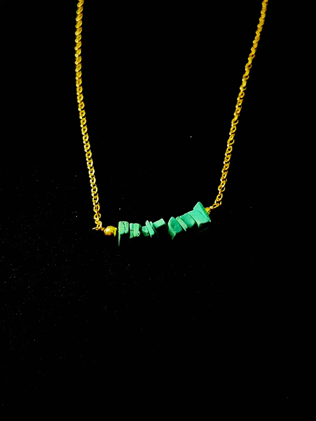 Close view of the Kinara raw turquoise chips and gold bead on a fine gold chain