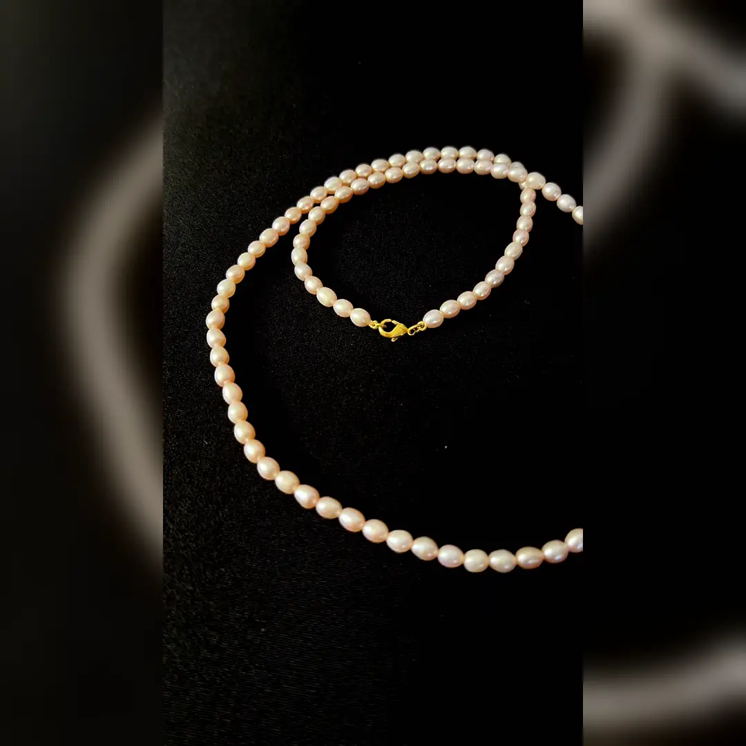 Moti pearl mala coiled, showing the soft blush lustre of the freshwater pearls
