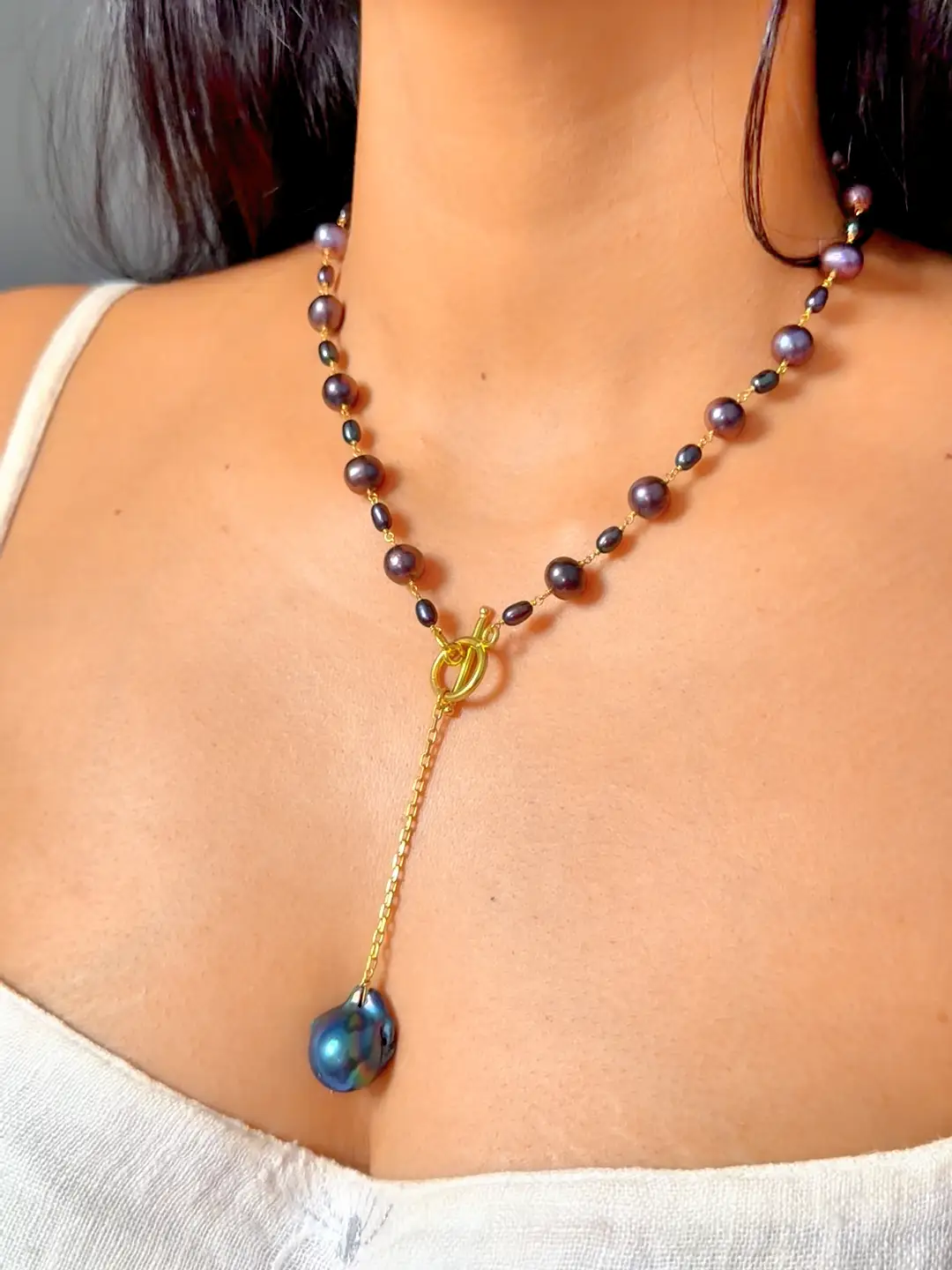 Nisha black pearl lariat necklace worn, the front toggle and baroque pearl drop at the collarbone