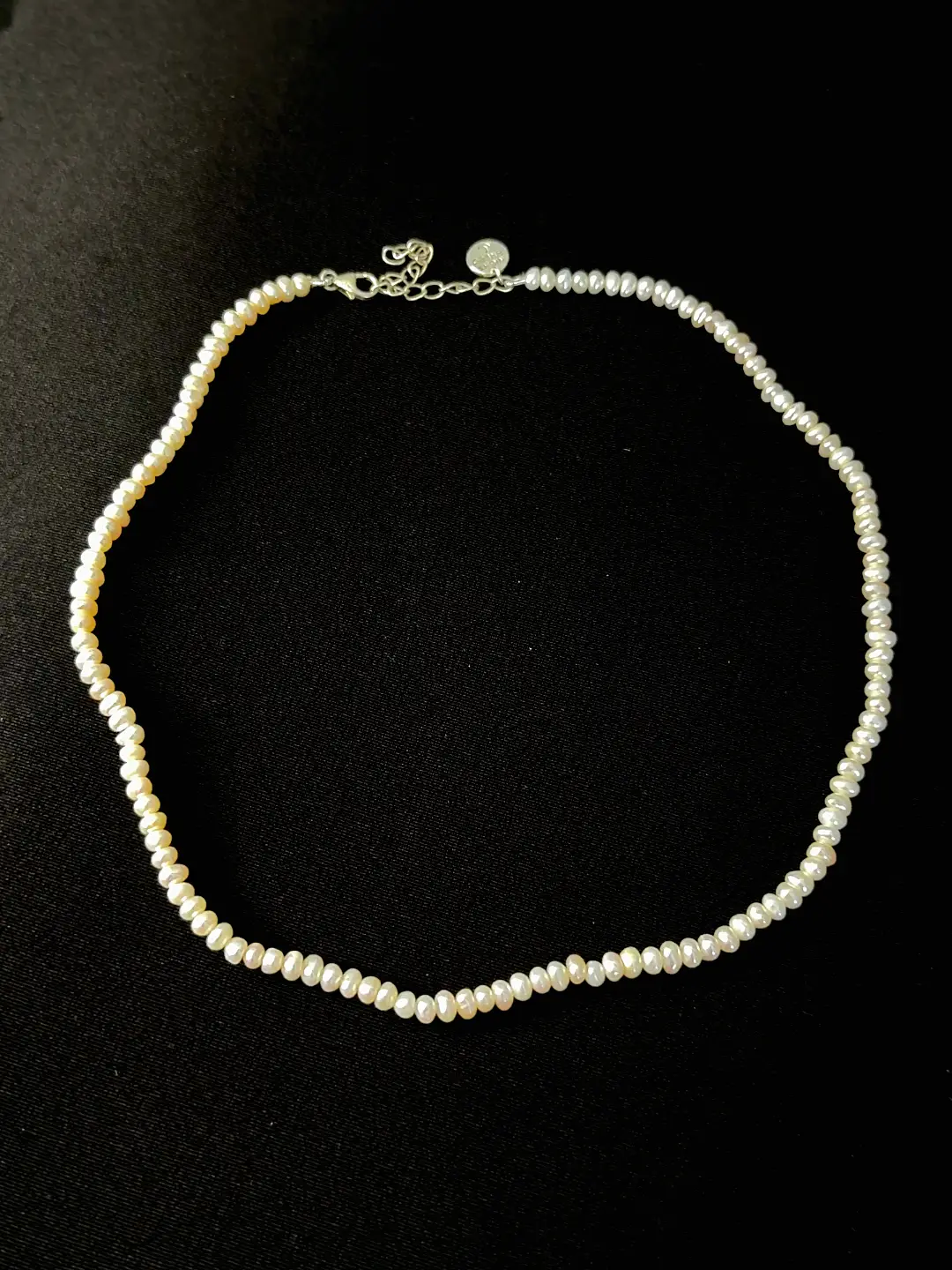 The Noor pearl choker laid out in a circle, silver-tone clasp and extender visible
