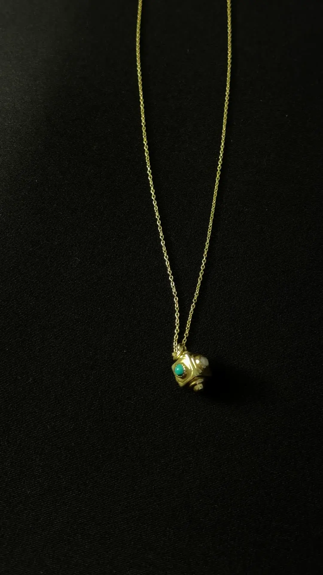 Pasa pendant — a tiny gold cube with turquoise set into its face