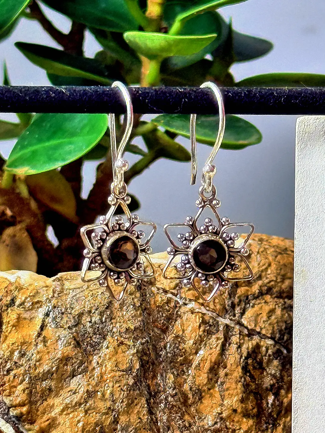 Tara star drop earrings shown hanging, catching daylight